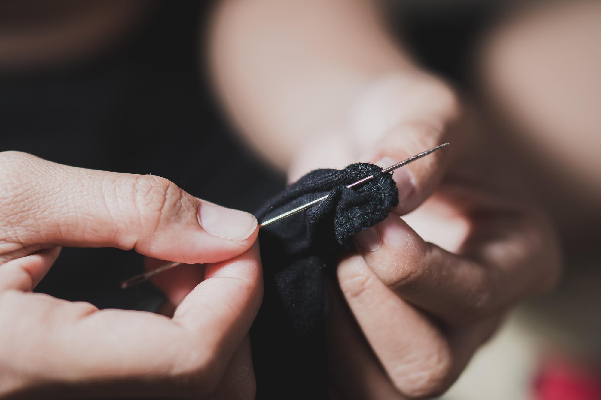 Artisan hands stitching decorative embroidery in workshop